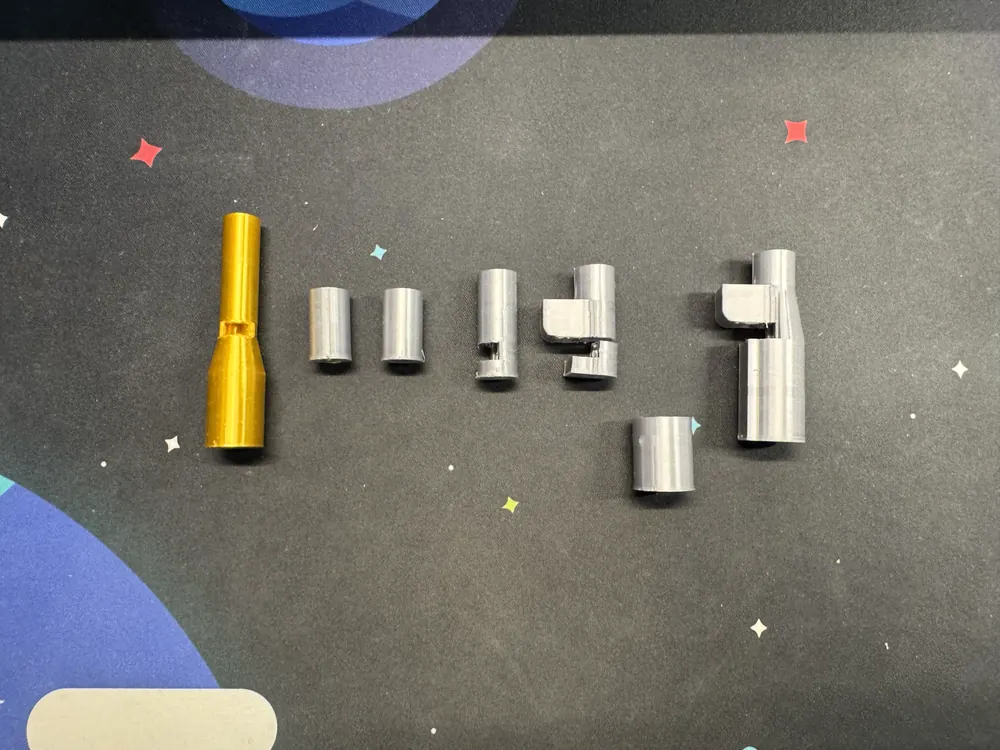 Barrel versions in a row: the gold freshman barrel, then grey test prints growing into the final v5 barrel.